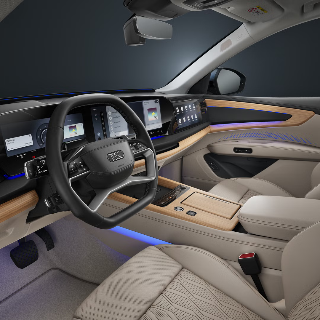 Blick ins Cockpit des Audi Q7 SUV mit schwarzem Lenkrad, Touchscreen, Lederausstattung und blauem Interaktionslicht.