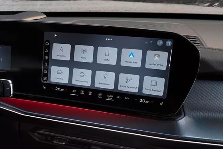 Das Bild zeigt den Innenraum eines Audi Q3 SUV und einen großen Bildschirm auf der Mittelkonsole. Auf dem Bildschirm sind verschiedene Bedienungsoptionen für Navigation, Radio, Smartphone-Integration und Fahrzeugfunktionen sichtbar. Links vom Bildschirm ist teilweise das Lenkrad zu sehen.